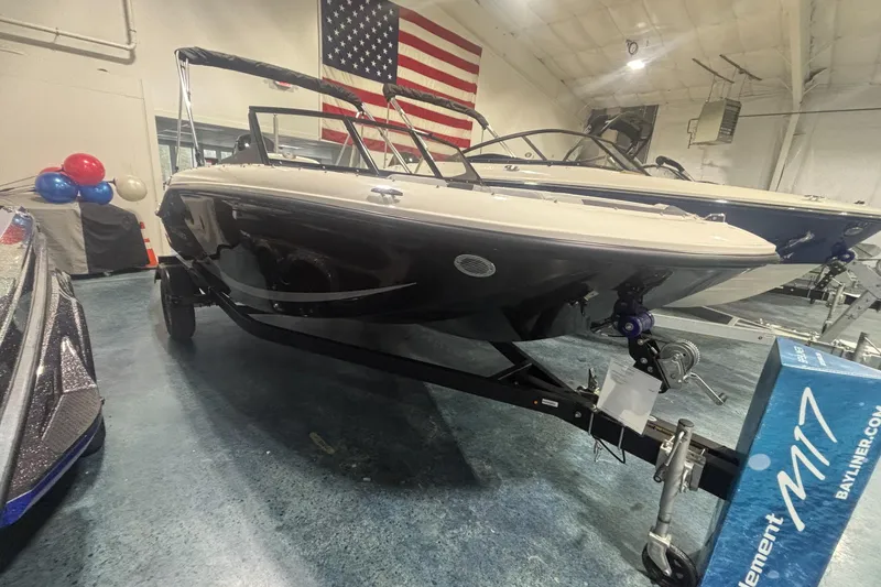 The Image of 2026 Bayliner M17 boat on display indoors with American flag backdrop. - 0