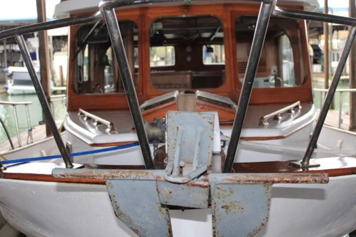 Slide: The Image of 1976 CHB Double Cabin Trawler with wooden accents and metal railings at a marina. - 10