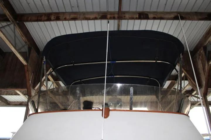 Slide: The Image of 1976 CHB Double Cabin Trawler under a covered dock, featuring a dark canopy. - 12