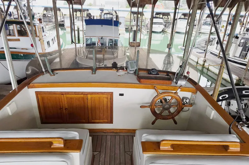 Slide: The Image of 1976 CHB Double Cabin Trawler helm with wooden wheel, docked in marina. - 14