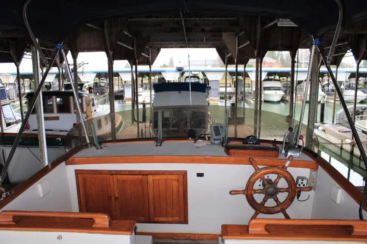 Slide: The Image of 1976 CHB Double Cabin Trawler interior with wooden helm, docked in a marina. - 15