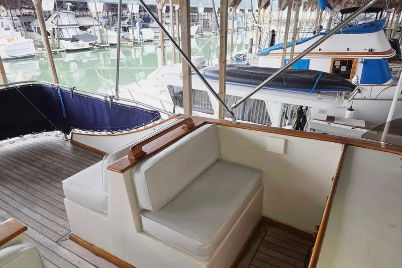 Slide: The Image of 1976 CHB Double Cabin Trawler interior with cushioned seating, docked in a marina. - 18