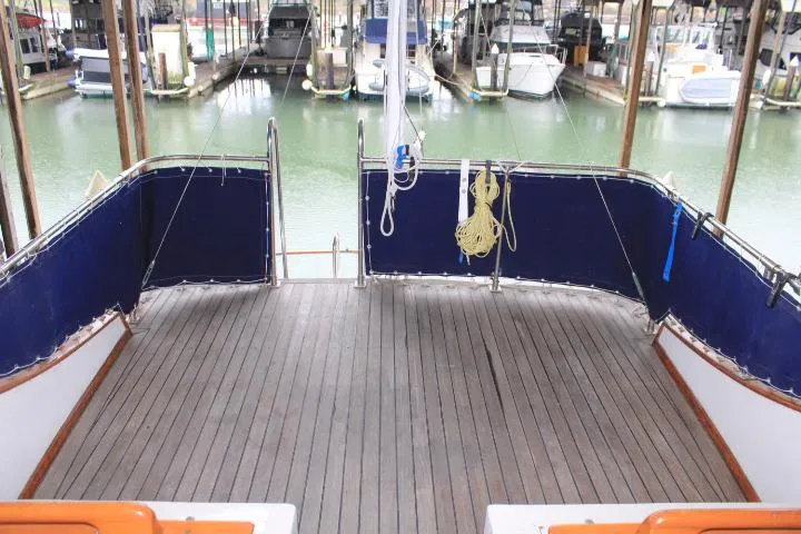 Slide: The Image of 1976 CHB Double Cabin Trawler deck with blue railings, docked in a marina. - 20