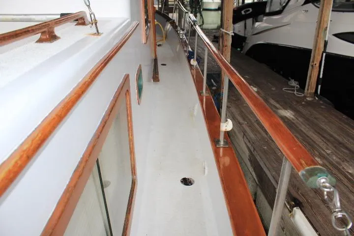 Slide: The Image of 1976 CHB Double Cabin Trawler deck with wooden railings and docked alongside. - 25