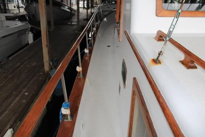 Slide: The Image of 1976 CHB Double Cabin Trawler deck with wooden railings in a marina. - 26