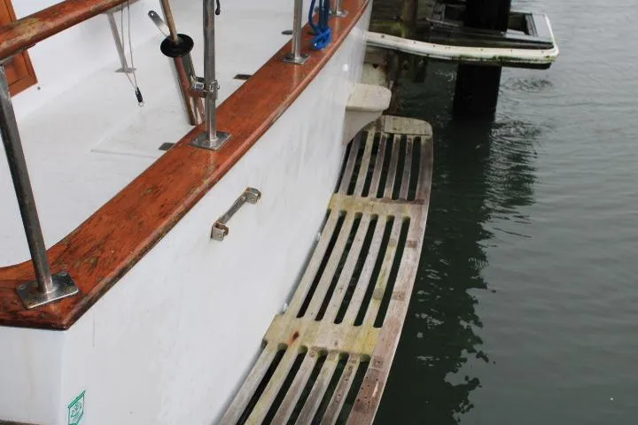 Slide: The Image of 1976 CHB Double Cabin Trawler with wooden deck and railing, docked by the water. - 30