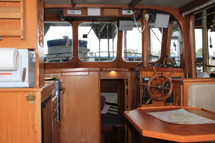 Slide: The Image of 1976 CHB Double Cabin Trawler interior with wooden helm, navigation equipment, and dining area. - 41