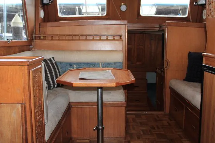 Slide: The Image of 1976 CHB Double Cabin Trawler interior with wooden furnishings and cozy seating area. - 62