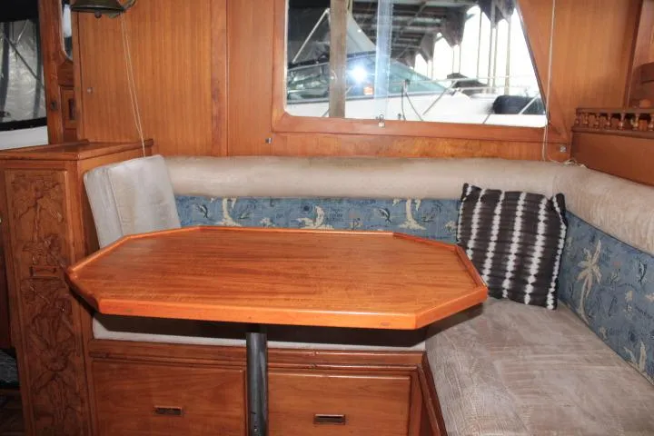 Slide: The Image of 1976 CHB Double Cabin Trawler interior with wooden table and cushioned seating. - 63
