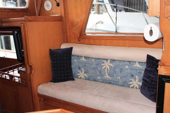 Slide: The Image of 1976 CHB Double Cabin Trawler interior with cushioned seating and nautical-themed decor. - 68