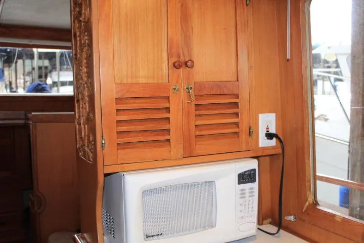 Slide: The Image of Wooden cabinet and microwave inside a 1976 CHB Double Cabin Trawler boat. - 72