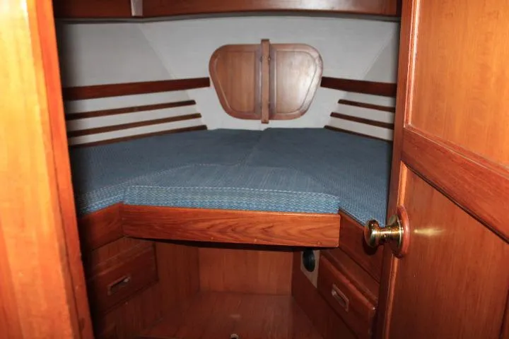 Slide: The Image of 1976 CHB Double Cabin Trawler interior with wooden finish and blue bedding. - 74
