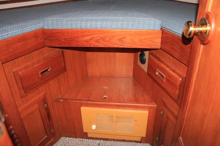 Slide: The Image of 1976 CHB Double Cabin Trawler interior with wooden cabinetry and blue cushioned bed. - 76