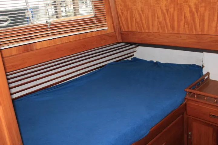 Slide: The Image of 1976 CHB Double Cabin Trawler interior with wooden finish and blue bedding. - 87