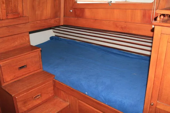 Slide: The Image of 1976 CHB Double Cabin Trawler interior with wooden finish and blue bedding. - 88