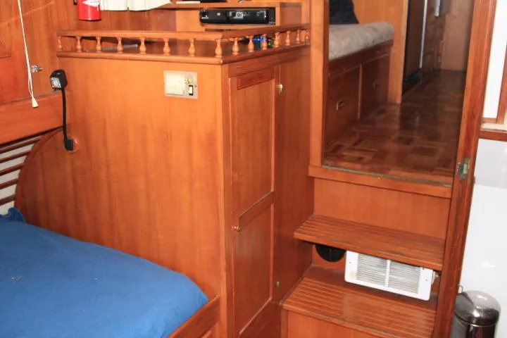 Slide: The Image of Interior of 1976 CHB Double Cabin Trawler with wooden furnishings and blue bedding. - 89