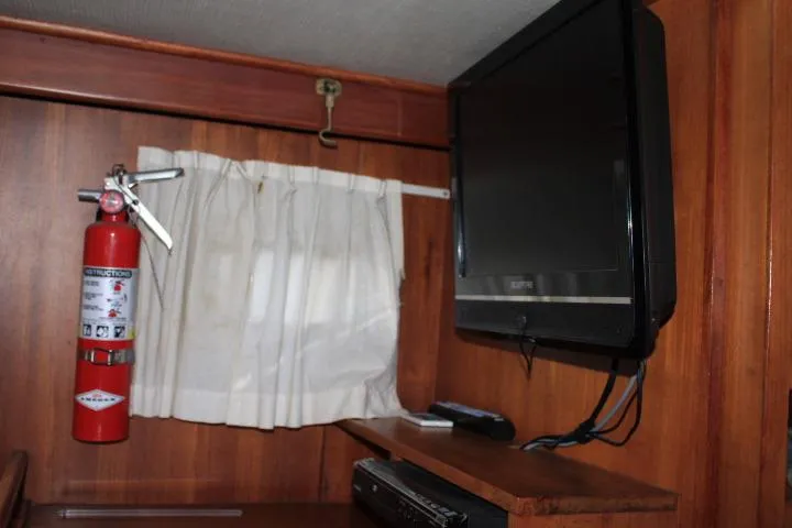 Slide: The Image of 1976 CHB Double Cabin Trawler interior with TV, fire extinguisher, and curtain. - 91