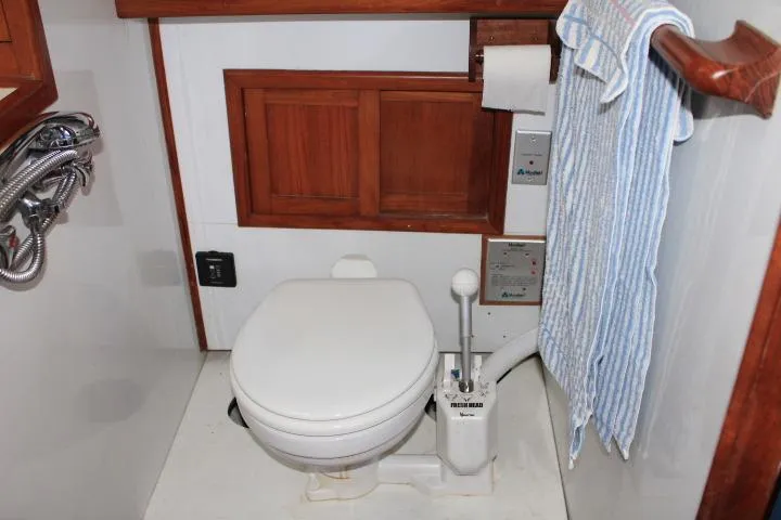 Slide: The Image of 1976 CHB Double Cabin Trawler bathroom with toilet, wooden accents, and striped towel. - 95