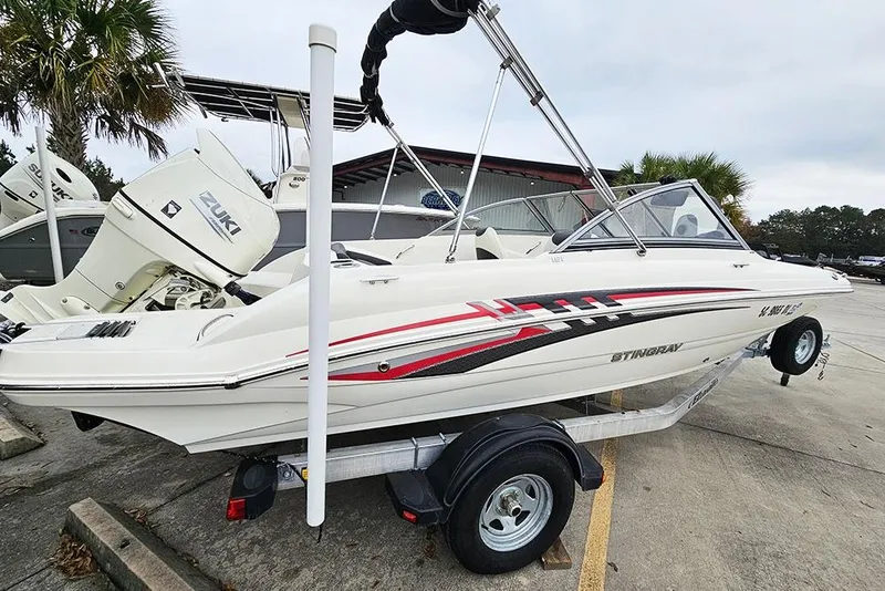Slide: The Image of 2019 Stingray 191 DC boat on trailer, featuring Suzuki outboard motor, parked outdoors. - 6