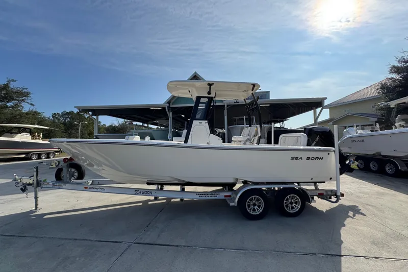 The Image of 2026 Sea Born LX24 Center Console boat on trailer in sunny marina. - 1