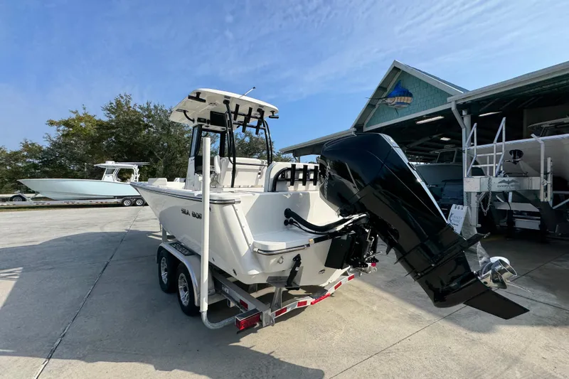 Slide: The Image of 2026 Sea Born LX24 Center Console boat on trailer, parked outside a marina. - 16