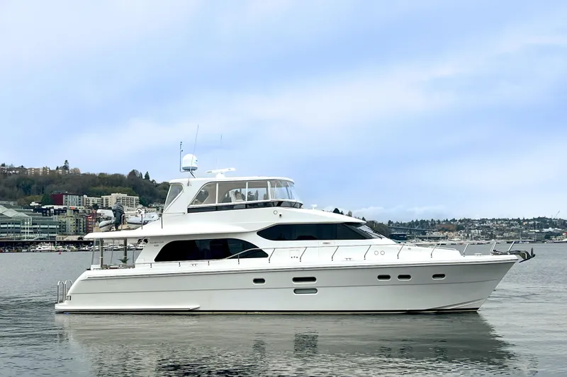 The Image of 2013 Hampton 620 Pilothouse yacht on calm water with cityscape background. - 0
