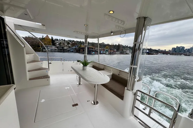 Slide: The Image of Luxurious 2013 Hampton 620 Pilothouse yacht deck with seating, table, and scenic waterfront view. - 8