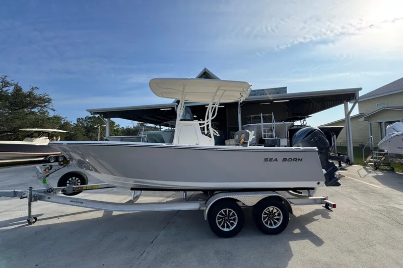 The Image of 2026 Sea Born LX21 Center Console boat on trailer, parked outdoors under clear sky. - 1