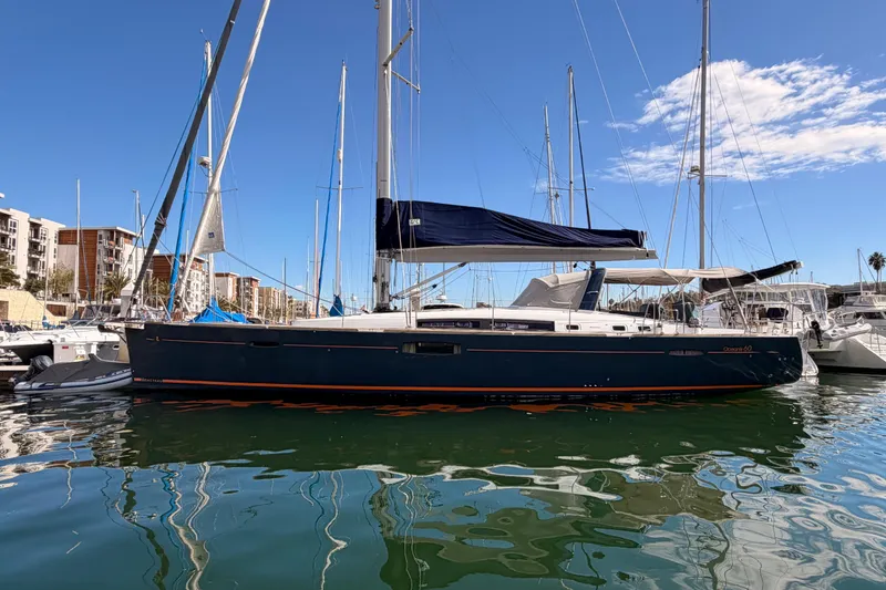The Image of 2015 Beneteau Oceanis Yacht 60 docked in a marina under clear blue skies. - 0