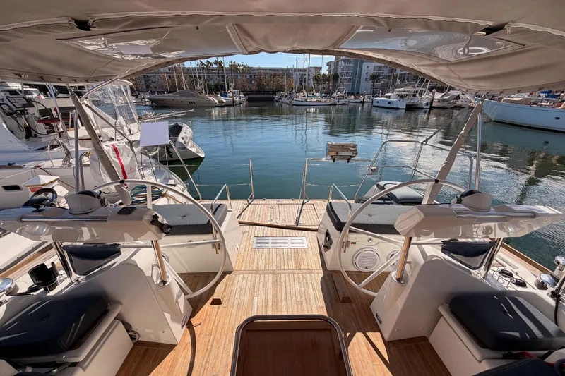 Slide: The Image of Beneteau Oceanis Yacht 60 cockpit view, showcasing dual steering wheels and marina backdrop. - 20