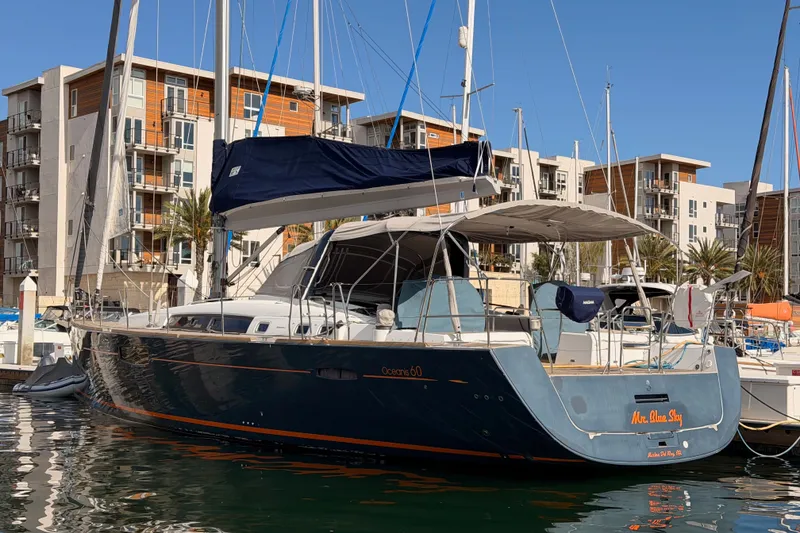 Slide: The Image of 2015 Beneteau Oceanis Yacht 60 docked in a marina, modern buildings in background. - 3