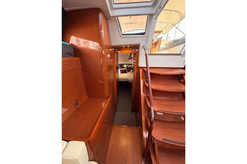 Slide: The Image of Interior view of 2015 Beneteau Oceanis Yacht 60, featuring elegant wooden finishes and staircase. - 61