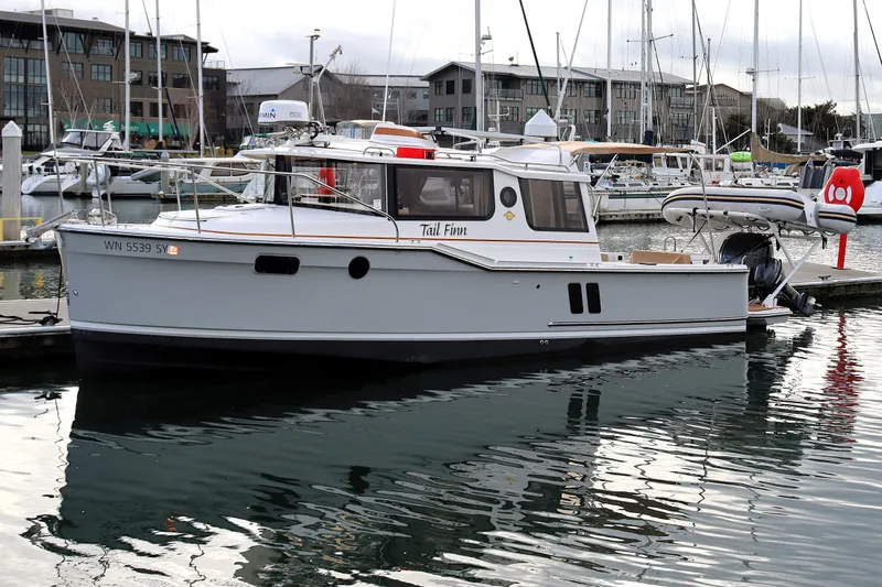 The Image of 2021 Ranger Tugs R-27 boat docked in marina, surrounded by other vessels. - 0