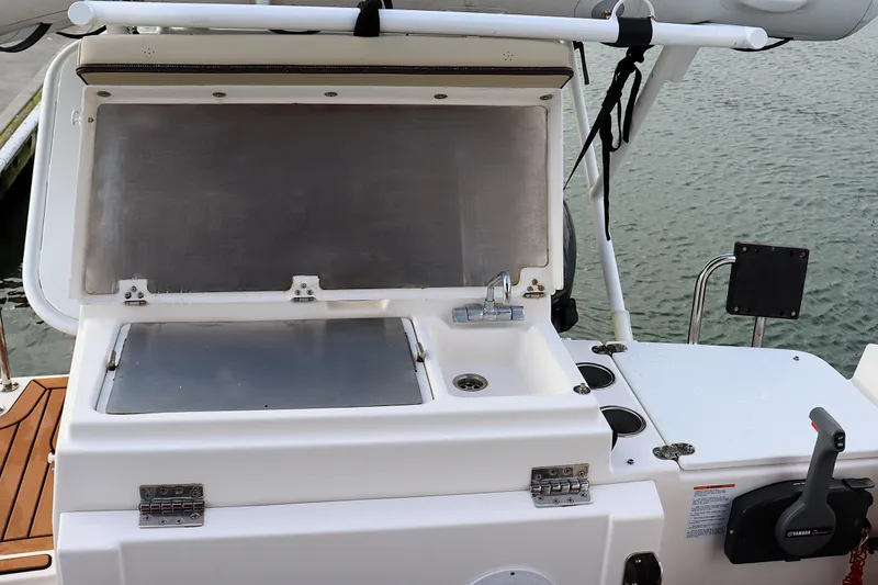 Slide: The Image of 2021 Ranger Tugs R-27 boat galley with sink and storage, docked by water. - 12