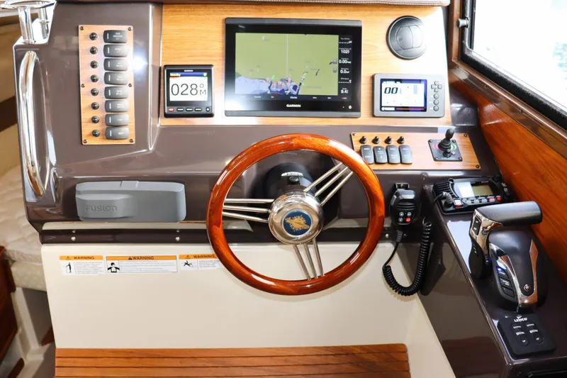 Slide: The Image of 2021 Ranger Tugs R-27 helm with navigation screens, wooden steering wheel, and control panel. - 14
