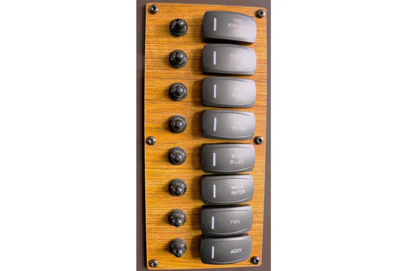 Slide: The Image of Control panel of 2021 Ranger Tugs R-27 with labeled switches on wood finish. - 16