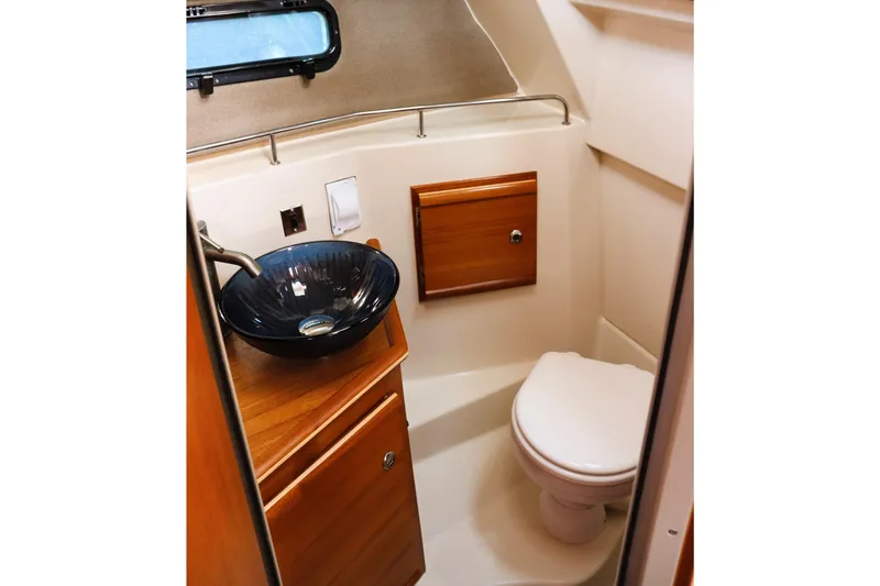 Slide: The Image of 2021 Ranger Tugs R-27 boat bathroom with modern sink and wooden cabinetry. - 21