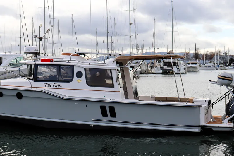 Slide: The Image of 2021 Ranger Tugs R-27 boat docked in marina, surrounded by sailboats. - 3