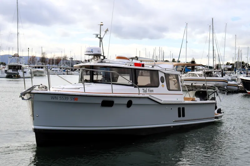 Slide: The Image of 2021 Ranger Tugs R-27 boat docked in a marina, surrounded by other vessels. - 8