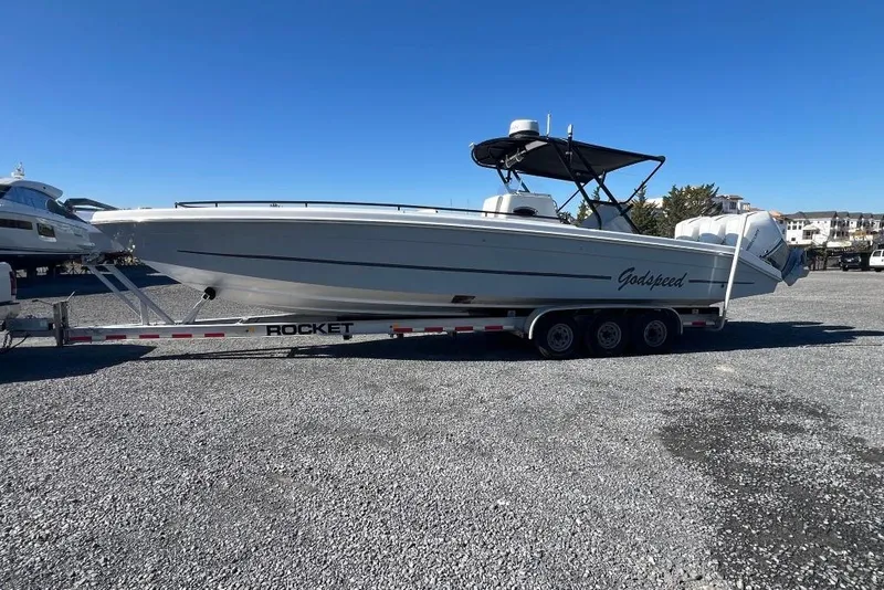 Slide: The Image of 2006 Dakota 36 Open boat on trailer, parked on gravel lot under clear blue sky. - 6