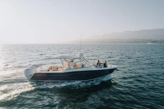 Slide: The Image of 2021 Grady-White Freedom 307 boat cruising on open water, scenic backdrop. - 1