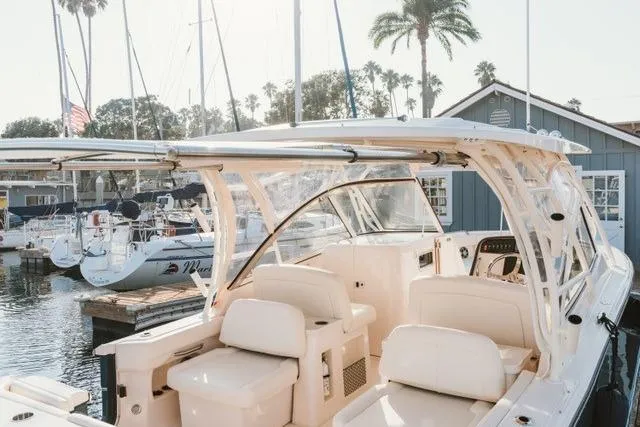 Slide: The Image of 2021 Grady-White Freedom 307 boat docked at a marina with sailboats and palm trees. - 2