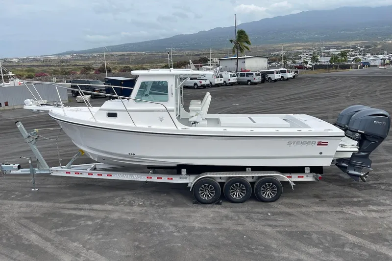 The Image of 2026 Steiger Craft 28 Hawaii boat on trailer, parked in a marina with mountain backdrop. - 2