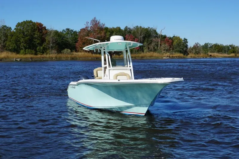 Slide: The Image of 2019 Key West 244 Center Console boat on a serene lake with trees in the background. - 2