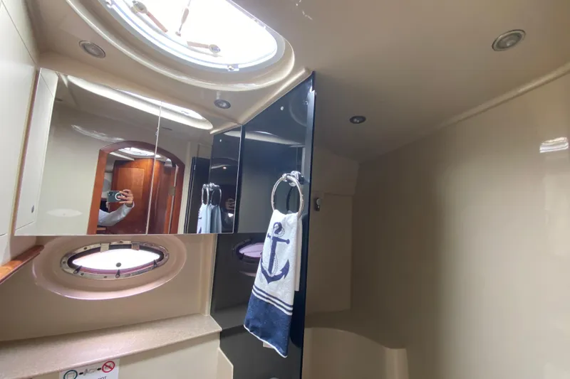 Slide: The Image of 2007 Cruisers Yachts 370 Express bathroom with porthole, mirror, and nautical-themed towel. - 48