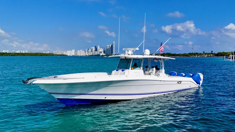 Slide: The Image of 2019 HCB 42 Siesta boat cruising on blue water with city skyline in background. - 25