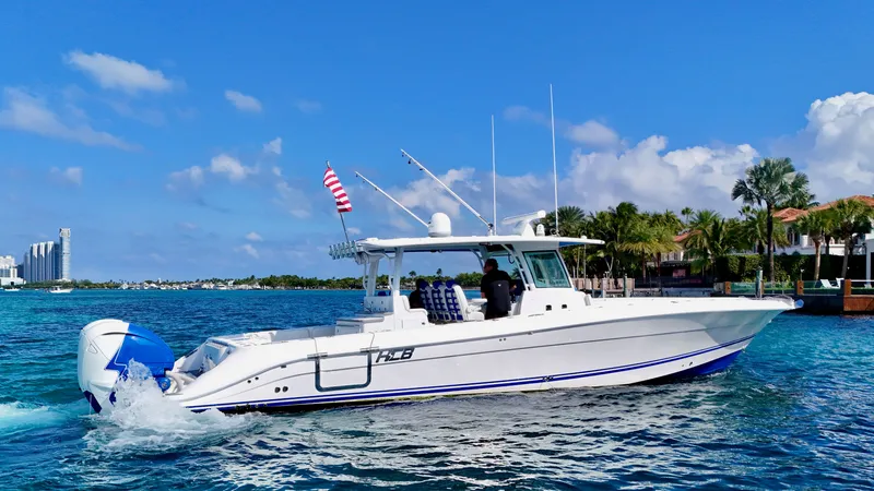 Slide: The Image of 2019 HCB 42 Siesta boat cruising on clear blue water, with cityscape and palm trees in background. - 28