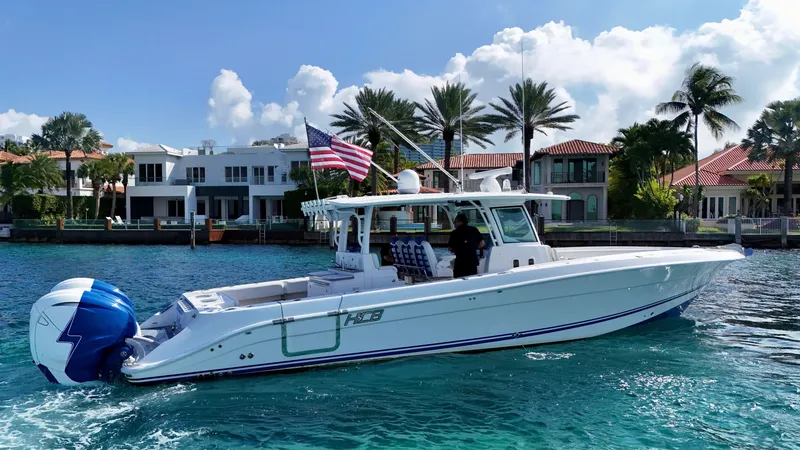 Slide: The Image of 2019 HCB 42 Siesta boat cruising near luxury waterfront homes, American flag displayed. - 31