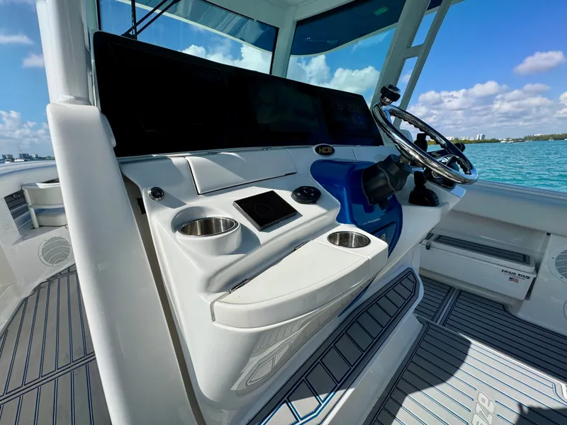 Slide: The Image of 2019 HCB 42 Siesta boat helm with steering wheel, cup holders, and ocean view. - 59