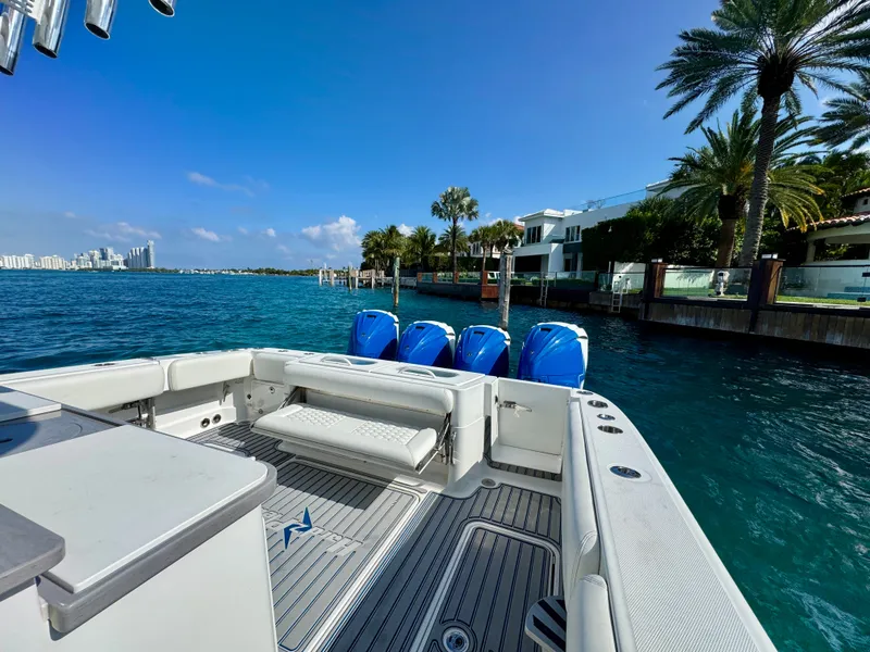 Slide: The Image of 2019 HCB 42 Siesta boat with four engines, docked near waterfront homes and palm trees. - 74